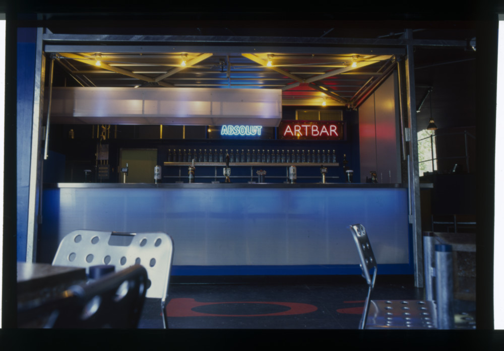image of the 1995 ArtBar, with a metallic bar, original ArtBar red neon sign and Absolut Vodka neon sign