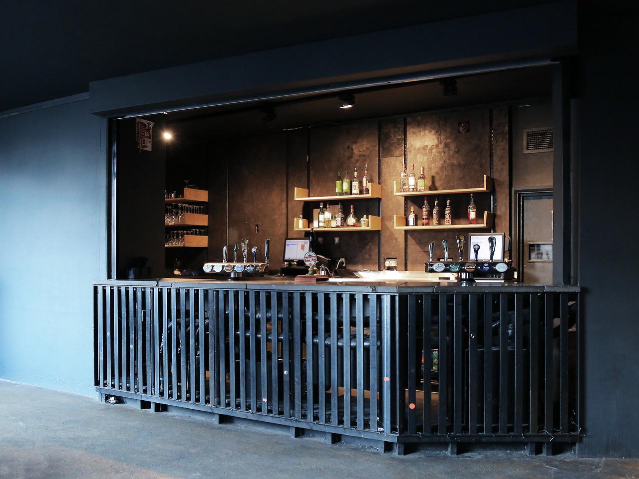 image of the 2016 ArtBar, minimalist dark look, with bar made of metal grating, concrete floor.