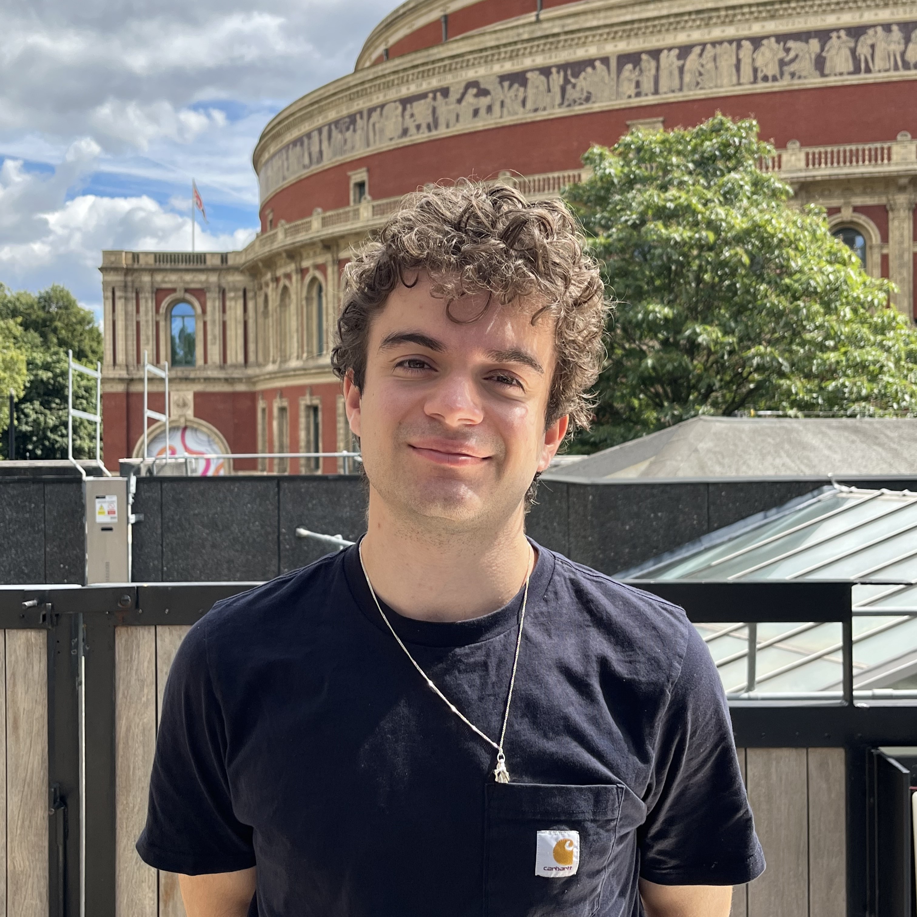 A photograph of Thomas stood in front of the Royal Albert Hall